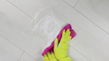 Sarı eldivenli eller yerden köpük temizliyor..