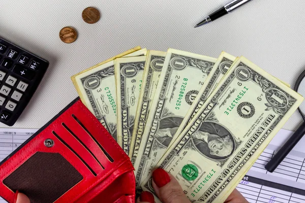 Kadın kırmızı cüzdanında para sayıyor.