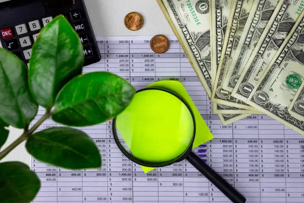 Para, post-it notu, büyüteç, hesap makinesi ve masaüstünde.