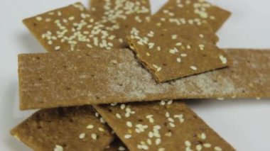 Taze organik çavdar gevrekleri ve susam tohumları beyaz bir tabakta dönüyor.