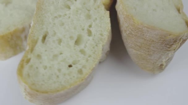 Kawałki świeżo upieczonego chleba pszennego obracają się na białym talerzu. — Wideo stockowe