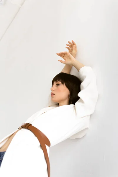 Beyaz ceketli güzel kadın stüdyoda poz veriyor.