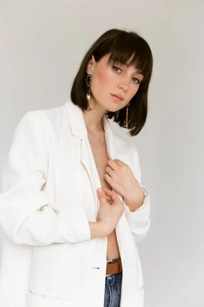 Beyaz ceketli güzel kadın stüdyoda poz veriyor.