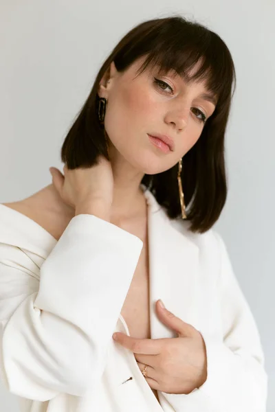 Beyaz ceketli güzel kadın stüdyoda poz veriyor.