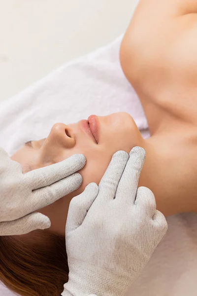 Kozmetik kliniğinde rahatlamış bir kadını yakından çek. Özel eldivenlerle mikro akım tedavisi görüyor..