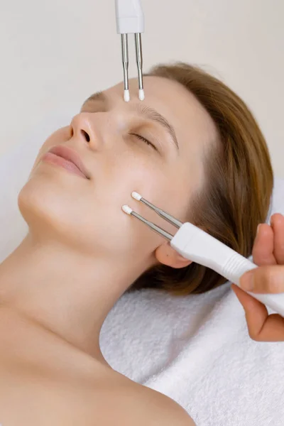 Yüz bakımı. Kozmetik kliniğinde rahatlamış bir kadına yaklaş. Mikro akım terapisi alıyor.