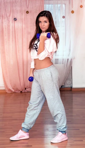 Young beautiful girl doing fitness with dumbbells in the gym — Stock Photo, Image