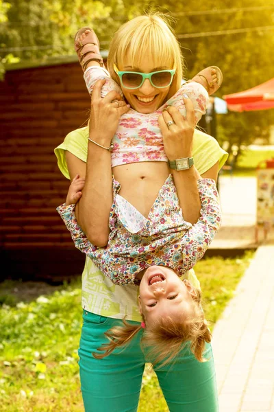 Beautiful smiling emotional mother and daughter playing in the park. (ektsrim, upside down, jack - concept).