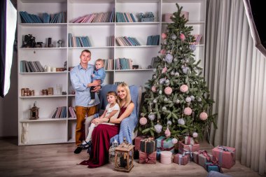 Genç bir aile profesyonel bir ışıkta yeni yıl fotoğraf çekimi yapıyor.