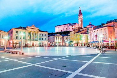 Slovenya 'nın turizm merkezi Piran' daki eski saat kulesi fenerlerin ışığında merkez meydandaki muhteşem şehir manzarası. Popüler turist eğlencesi. Harika, heyecan verici yerler. (tatil, dinlenme - kavram)