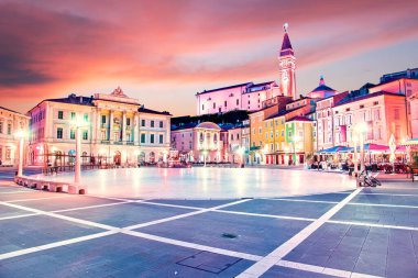 Slovenya 'nın turizm merkezi Piran' daki eski saat kulesi fenerlerin ışığında merkez meydandaki muhteşem şehir manzarası. Popüler turist eğlencesi. Harika, heyecan verici yerler. (tatil, dinlenme - kavram)