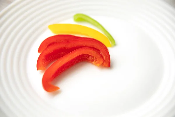 Bulgaro rosso verde giallo pepe fette su piatto bianco — Foto Stock