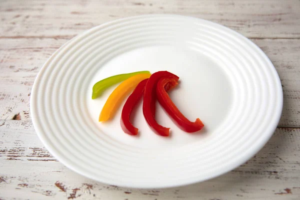 Bulharská červená zelená žlutá paprika plátky na bílém talíři — Stock fotografie