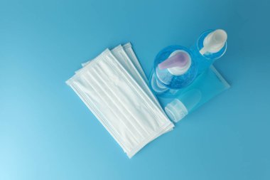 Alkol jeli şişeleri, beyaz tıbbi maskeli el dezenfektanı ve mavi arka plan manzaralı düz bir zemin. Bu jel temizleyiciler antibakteriyel ve virüs hijyen için..
