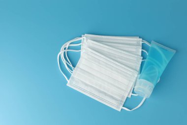 Alkol jeli şişesi, beyaz tıbbi maskeli el dezenfektanı ve mavi arka planda düz bir zemin. Bu jel temizleyiciler antibakteriyel ve virüs hijyen için..