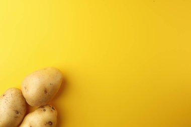 Sarı arka planda üç patates. Resim üst görünümü, düz görünüm ve boşluk kopyala.