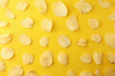 Sarı arka planda çıtır patates cipsi. Resim üst görünümü, düz la