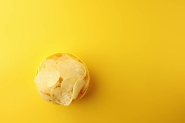 Sarı arka planda sarı bir kasede patates cipsi atıştırmalıkları. Resim üst görünümü, düz görünüm ve boşluk kopyala.