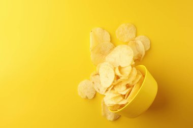 Sarı arka planda sarı bir kasede patates cipsi atıştırmalıkları. Resim üst görünümü, düz görünüm ve boşluk kopyala.