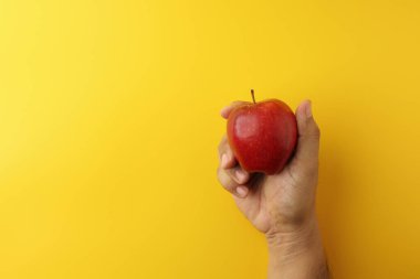 Sağ el, elinde kırmızı elmayla sarı arka planda fotokopi çeken bir adam. Taze bir his veriyor.