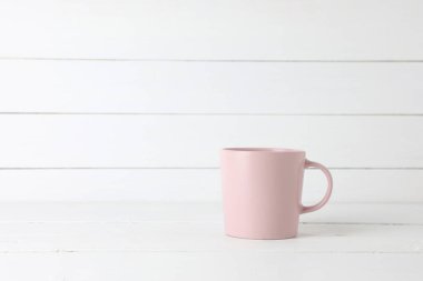 Beyaz ahşap arka planda, fotokopi saplı pembe kahve kupası..