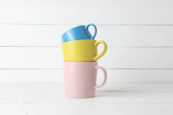 Штабелированные Синие Желтые Чашки Розовая Кофейная Кружка Белом Деревянном Фоне — стоковое фото