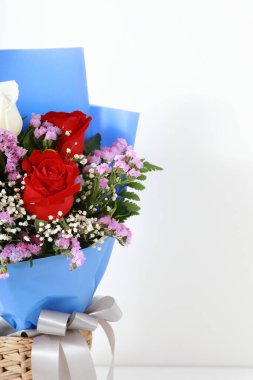 Hasır sepetteki gül buketini beyaz ahşap arka planda kapat. Kopya alanı, konsept sevgililer günü.