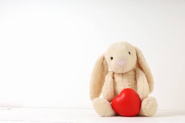 Beyaz arka planda kırmızı kalbi olan kahverengi tavşan bebek..