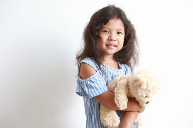 Küçük kız oyuncak ayıyı izole etti. Gülümsüyor beyaz arka planda.