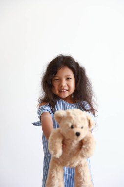 Küçük kız izole edilmiş bir oyuncak ayı göndermiş. Gülümsüyor Mutlu duruyor beyaz arka planda.