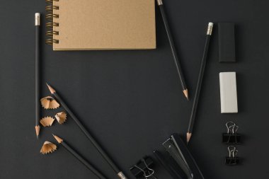 Ofis kağıtları, ataç kağıdı, silgi, siyah masa üzerindeki kalem düzlüğü. Üst görünümde kopyalama alanı var.