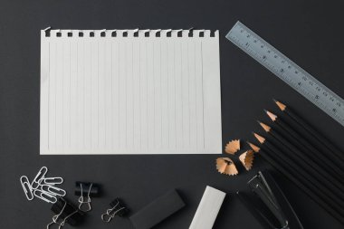 Ofis kırtasiyesi, ataç kağıdı, silgi, kalem, cetvel, siyah masa düz yatıyordu..