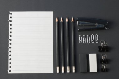 Ofis kağıtları, ataç kağıdı, silgi, siyah masa üzerindeki kalem düzlüğü. Üst görünümde kopyalama alanı var.