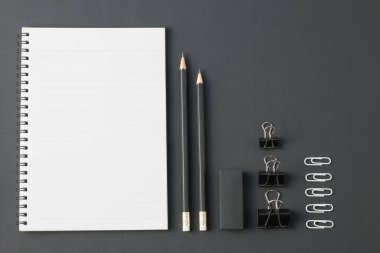 Ofis kağıtları, ataç kağıdı, silgi, siyah masa üzerindeki kalem düzlüğü. Üst görünümde kopyalama alanı var.