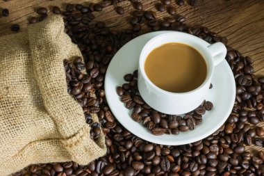 Kahve fincanı ve kahve çekirdekleri masa tahtasında. metin için boşluk kopyala.