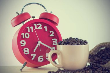 Kahve taneli pembe bardak ve kırmızı alarmlı saat. Resim vintage biçimi.