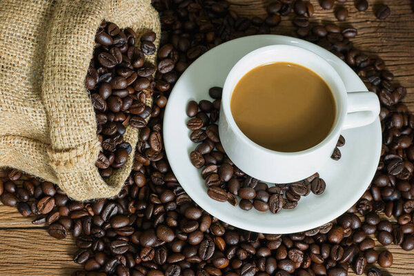 Coffee cup and coffee beans in sack on table wood. copy space for text.