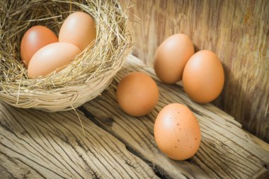 Bir yumurta ahşap arka planda ve yumurtalar hasır sepetin arkasında. Metin yazmak için sağ tarafta kopyalama alanı ile.