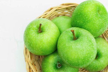 Hasır sepetteki taze yeşil elmalar. beyaz arkaplanda izole.