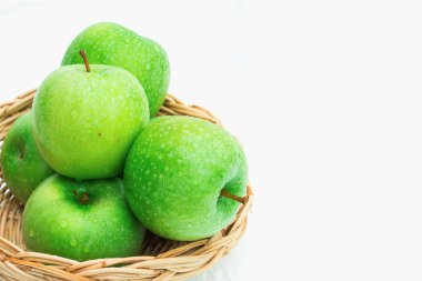 Hasır sepetteki taze yeşil elmalar. beyaz arkaplanda izole.