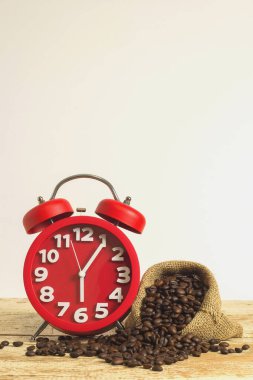 Beyaz arka plan tahtadan masada üzerinde kahve çekirdekleri olan kırmızı alarm saati. Metin yazmak için boşluk kopyala.