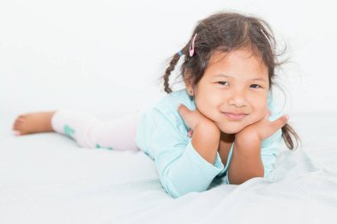 Güzel Asyalı çocuk yatağında mutlu bir şekilde gülümsüyor..