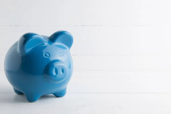 Blue piggy bank  on white wood background. copy space.