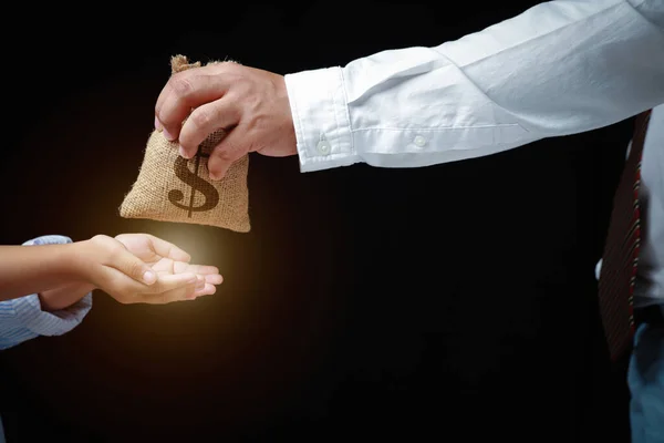 İşadamı çocuğuna bir çuval para yolluyordu, iki eli uzanmış siyah bir arka plana uzanıyordu. Gelecekteki bursları için kullanılacak..