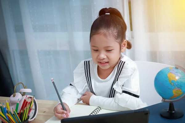 家庭でオンラインで学ぶアジアの子供たち コロナウイルス中の子供のための距離教育 彼女はビデオ通話を介して答えを書き 喜んで先生と通信笑顔 — ストック写真
