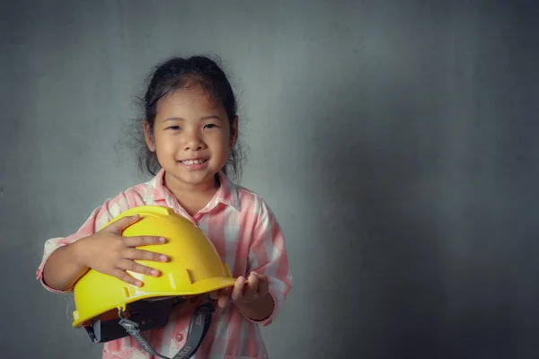 Geleceği hazırlamak için fikir ve ilham. Asyalı çocuğun kendine güveni tam. Elinde çimento arka planında fotokopi alanı olan sarı miğfer var. eğitim ve başlangıç kavramı.