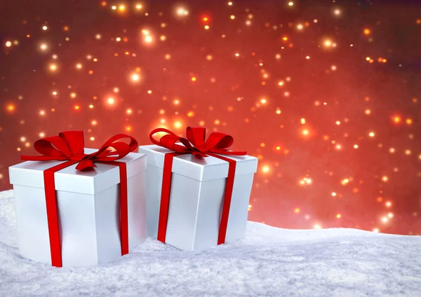 Christmas gifts in snow on bokeh red background. 3D render. — Stockfoto