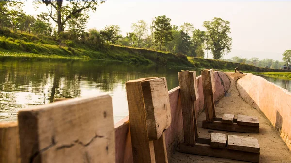Nepal 'deki Chitwan Ulusal Parkı' ndaki bir nehirde ahşap bir teknede tahta tabureler.