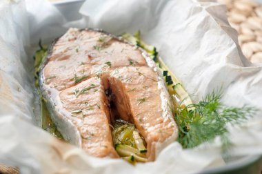 piece of fresh salmon cooked in papillote with herbs, zucchini and young onion clipart