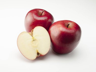Beyaz arka planda iki kırmızı elma ve bir kesik.
